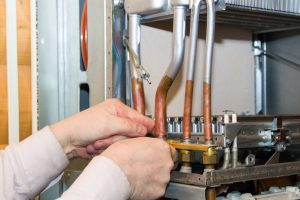 worker installs the heat exchanger after descaling on a workplace in the gas boiler